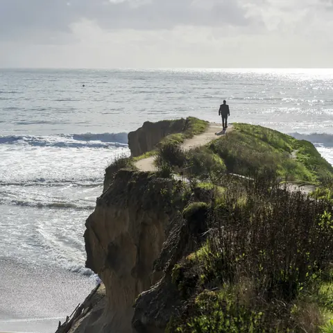 A traveler overlooking the sea from a coastal clifftop path